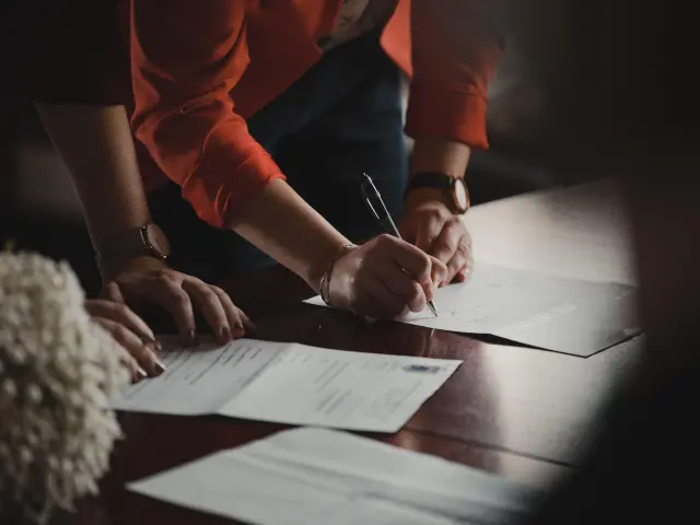 Deux personnes signent des documents sur une table