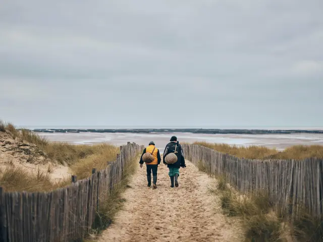 Deux personnes marchant sur un chemin de sable vers la mer à Annoville