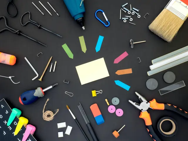 Divers outils et fournitures de bricolage disposés sur une surface noire
