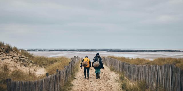 Deux personnes marchant sur un chemin de sable vers la mer à Annoville