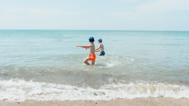 Deux enfants jouent dans les vagues de l'océan
