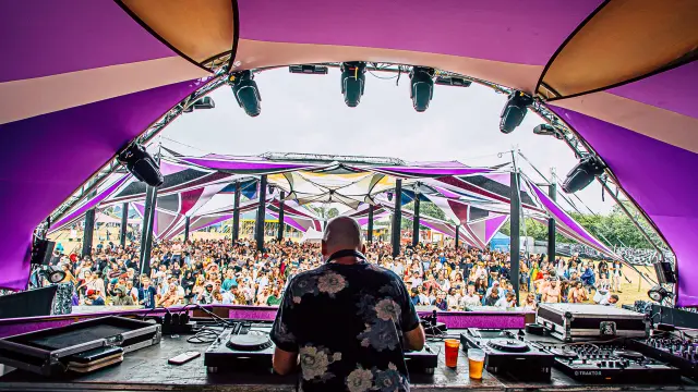 Un DJ en train de mixer devant une foule sous un chapiteau violet au doxart de Hambye
