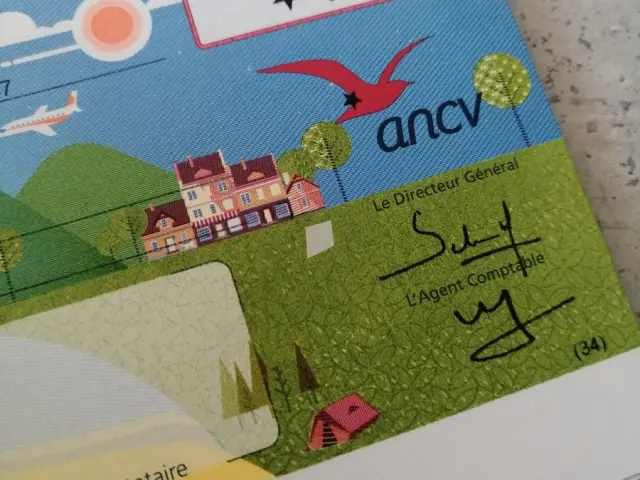 Un chèque de 10€ émis par ANCV avec des illustrations de paysages et de bâtiments
