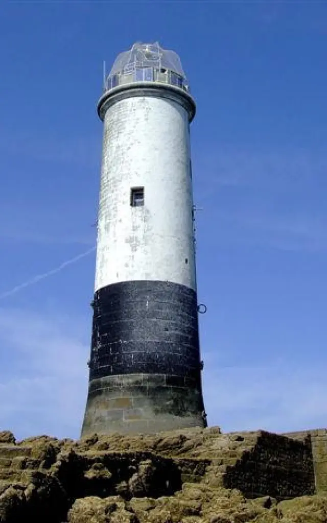 Un phare blanc et noir sur des rochers: le sénéquet