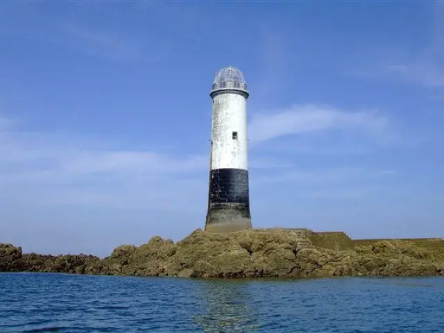 Phare blanc et noir sur des rochers au milieu de l'eau le sénéquet