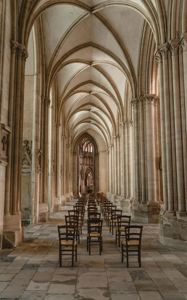 Nef de la cathédrale de Coutances avec des arcs en ogive et des rangées de chaises