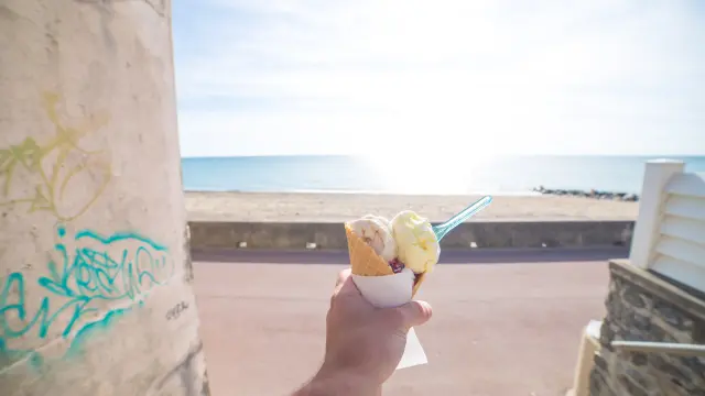 Une main tenant un cône de glace à deux boules à Agon Coutainville devant la mer