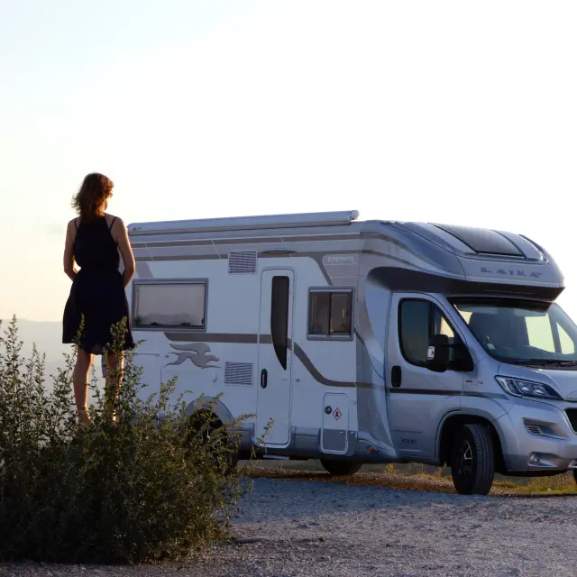 Femme debout près d'un camping-car à la campagne