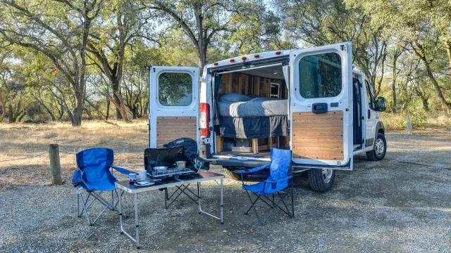 Un van aménagé avec des chaises et une table à l'extérieur dans un camping