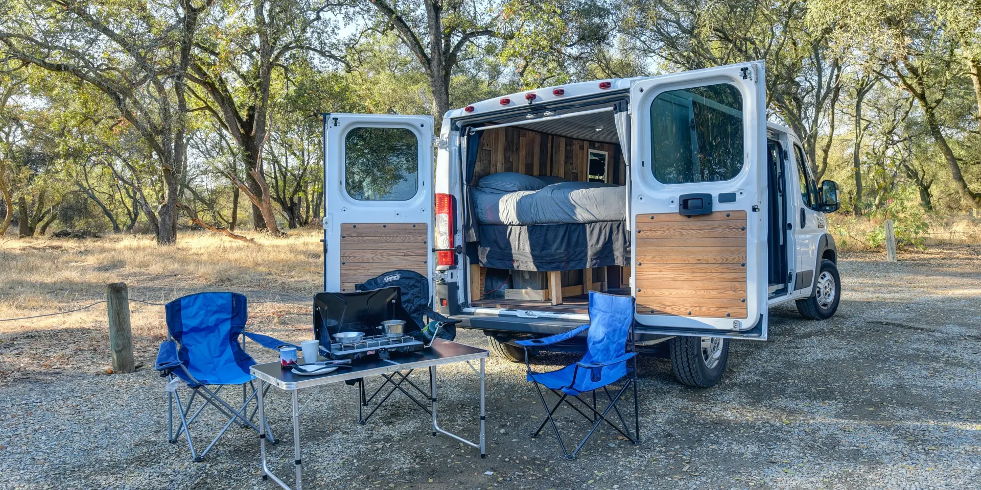 Un van aménagé avec des chaises et une table à l'extérieur dans un camping