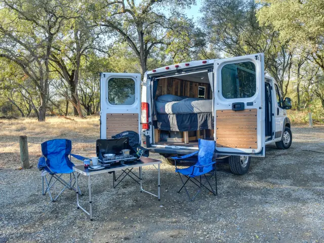 Un van aménagé avec des chaises et une table à l'extérieur dans un camping