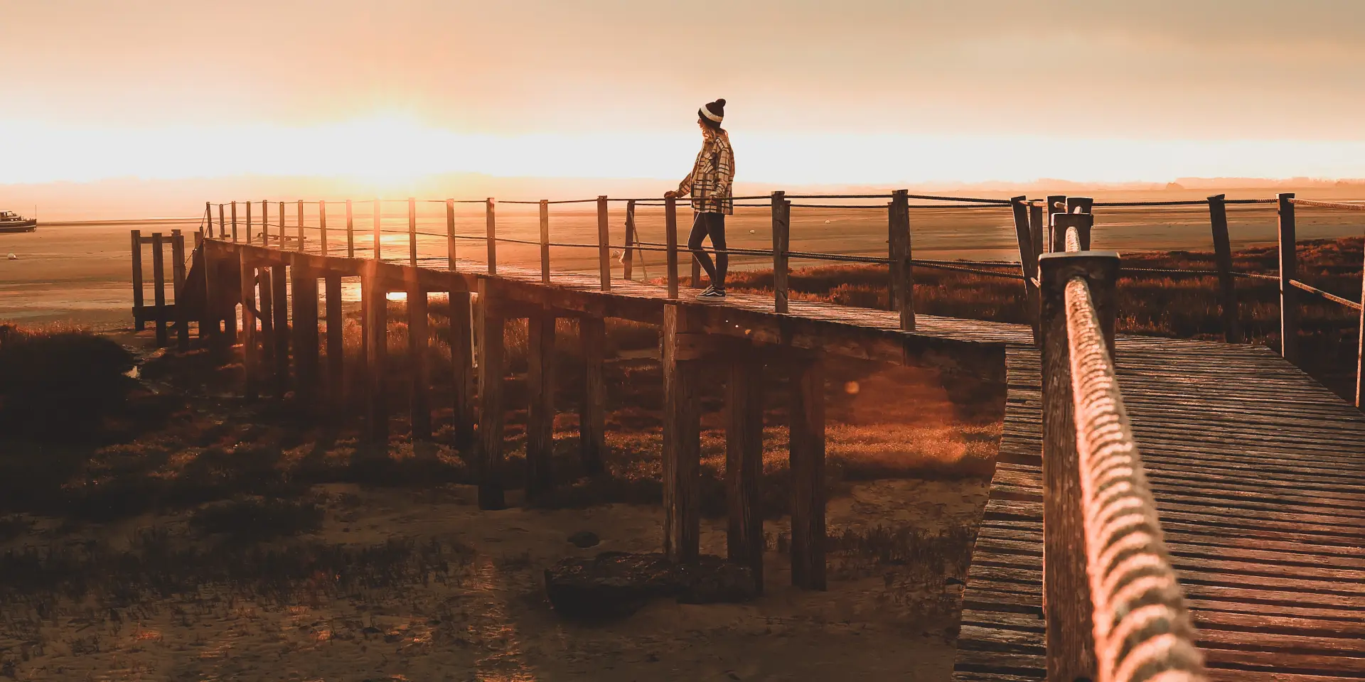 Personne debout sur un ponton en bois au coucher du soleil à la pointe d'Agon