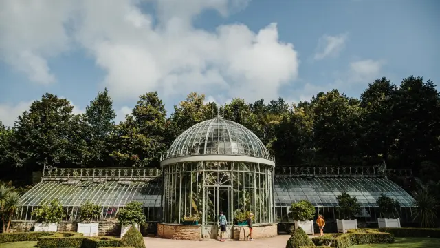 Grande serre en verre avec des plantes et des personnes à l'intérieur au chateau des Ravalet