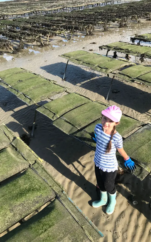 Young girl standing in a seaweed field with gloves and boots