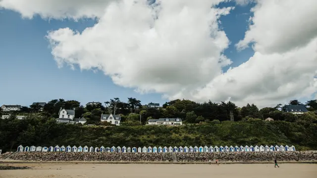 White beach huts lined up on a sandy beach