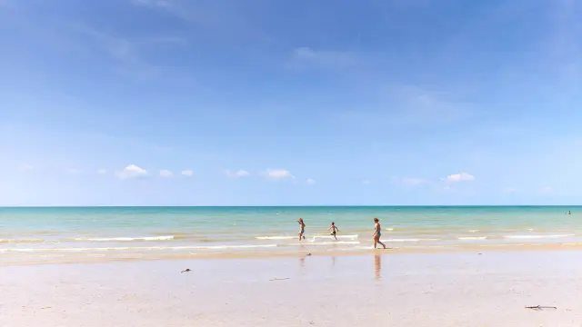Three children running on a fine sandy beach