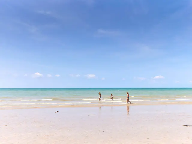 Three children running on a fine sandy beach