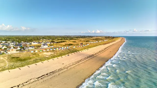A long sandy beach with houses and colorful beach cabins