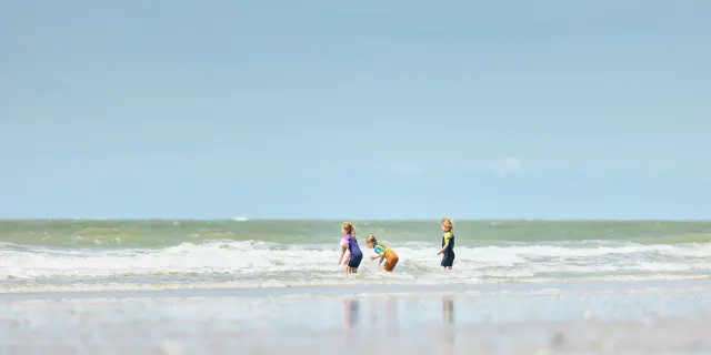 Drei Kinder spielen in den Wellen am Strand