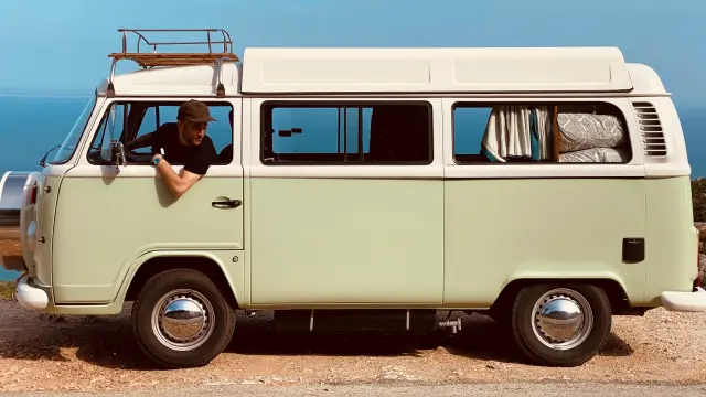 Un homme conduit un van vintage sur une route côtière