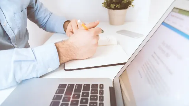 Personne travaillant sur un ordinateur portable avec un stylo