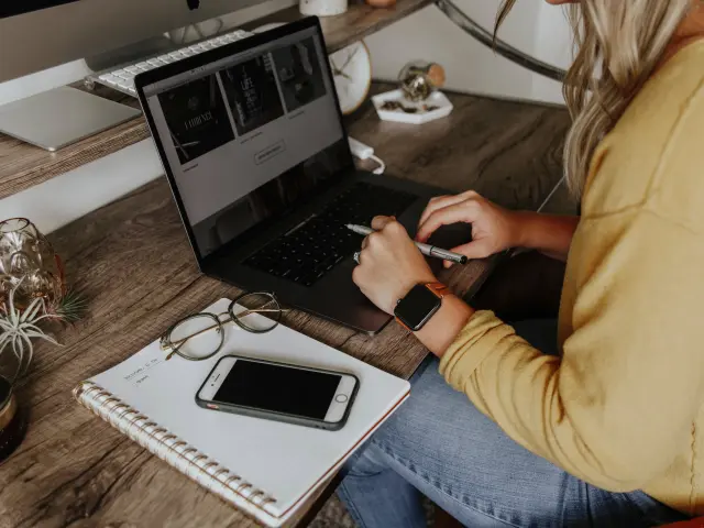 Une personne travaillant sur un ordinateur portable avec un smartphone et un carnet