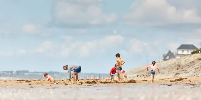 Enfants jouant sur une plage de sable avec des adultes à Hauteville sur Mer