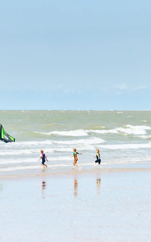 Enfants jouant sur la plage avec des vagues en arrière-plan à Hauteville sur Mer