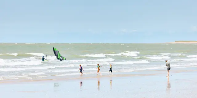 Enfants jouant sur la plage avec des vagues en arrière-plan à Hauteville sur Mer