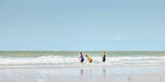 Three children playing in the waves on a beach