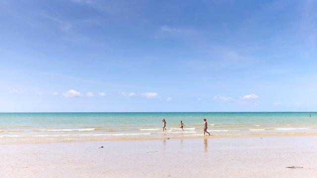 Drei Kinder laufen auf einem feinen Sandstrand