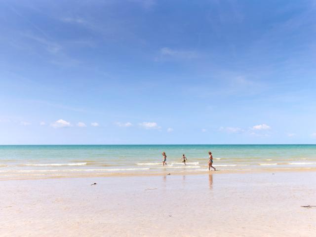 Three children running on a fine sandy beach
