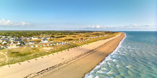 A long sandy beach with houses and colorful beach cabins