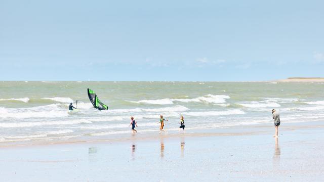 Enfants jouant sur la plage avec des vagues en arrière-plan à Hauteville sur Mer