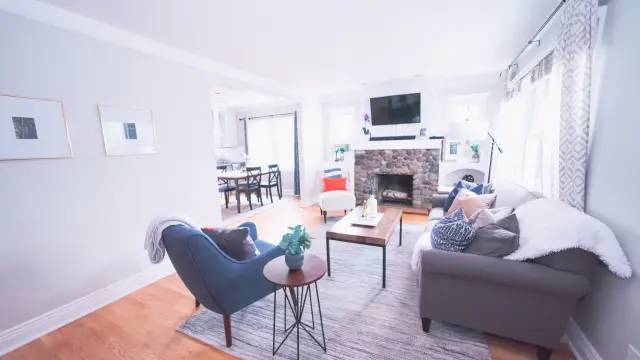 Salon moderne avec canapé gris, fauteuil bleu, table basse en bois et cheminée