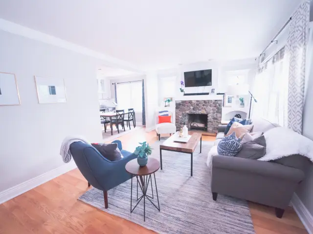 Salon moderne avec canapé gris, fauteuil bleu, table basse en bois et cheminée