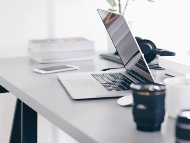 Bureau avec ordinateur portable, téléphone, tasses et appareils photo