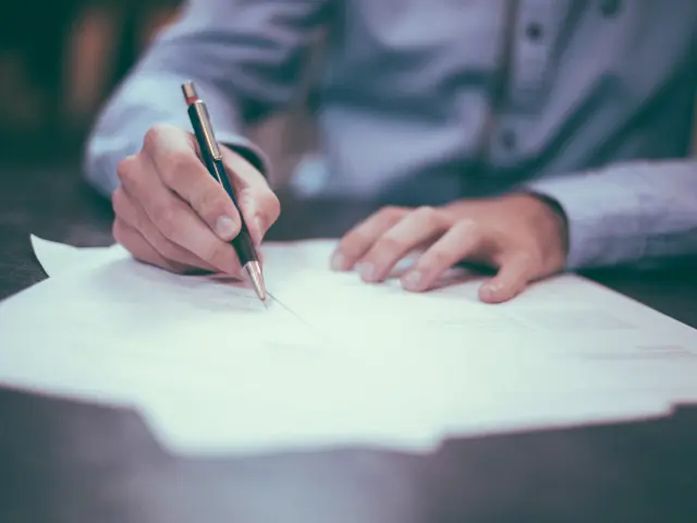 Une personne signe un document avec un stylo