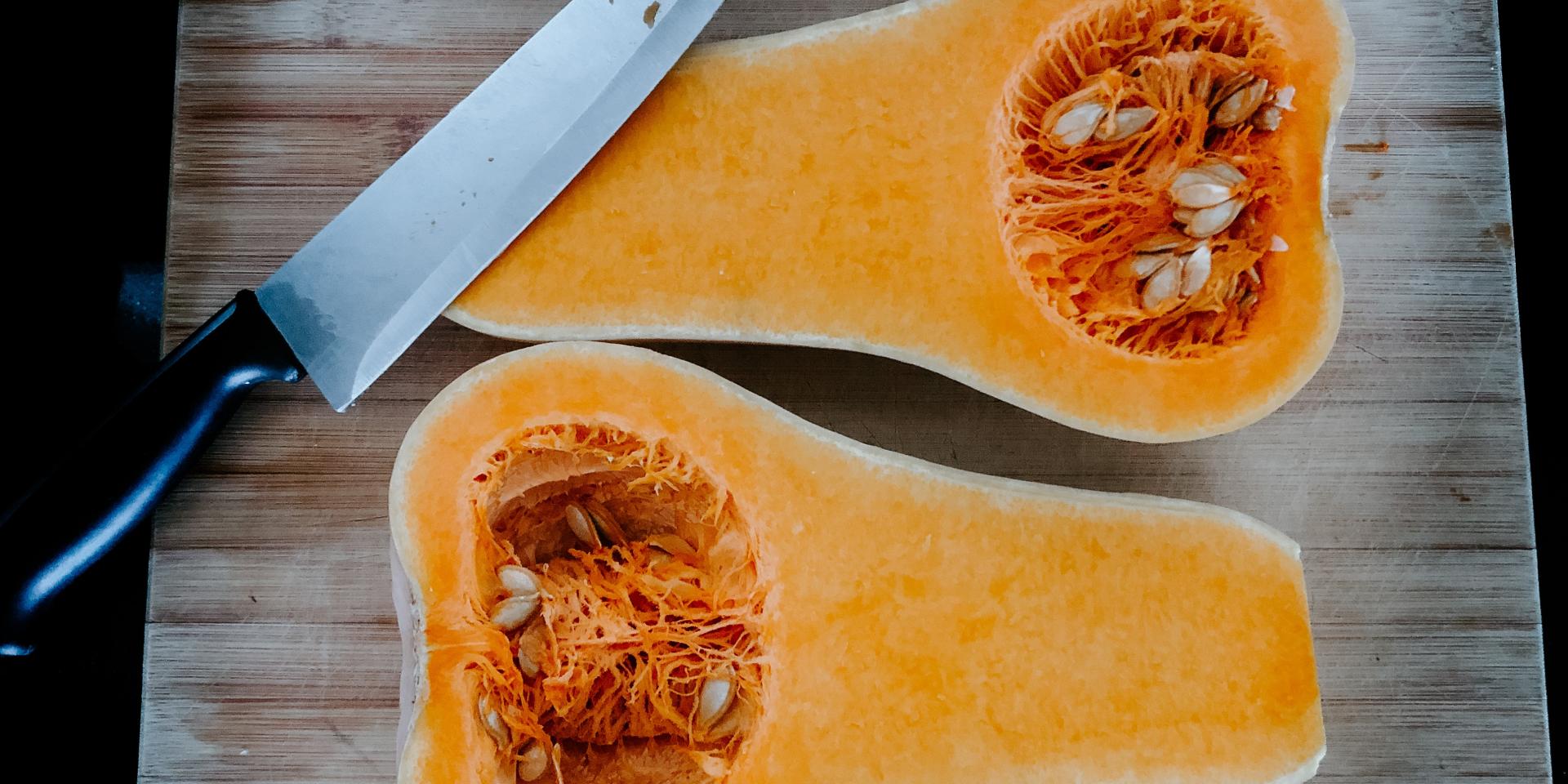 Deux moitiés de courge butternut sur une planche à découper avec un couteau