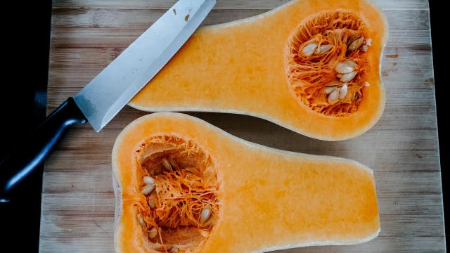 Deux moitiés de courge butternut sur une planche à découper avec un couteau