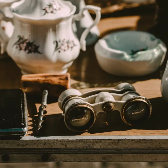 Binocle, tasse à café et autres objets vintage sur une étagère en bois