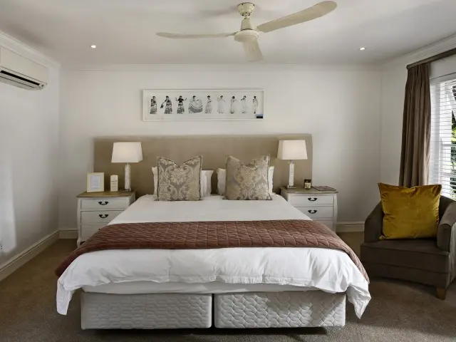 Chambre avec lit double, deux tables de chevet, un fauteuil et une décoration murale