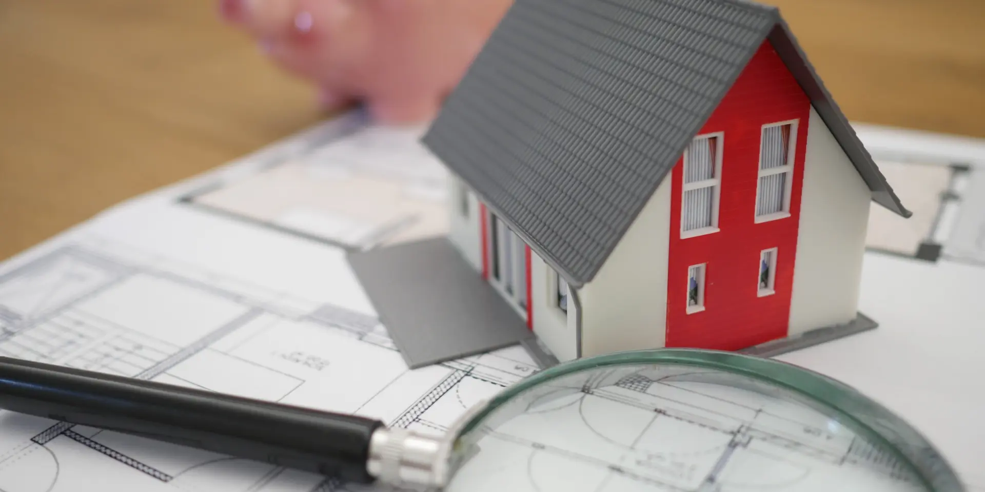 Maison miniature sur des plans de construction avec une loupe et un cochon tirelire