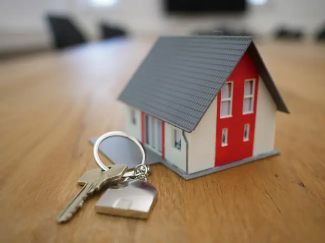 Maison miniature rouge et blanche avec des clés sur une table en bois