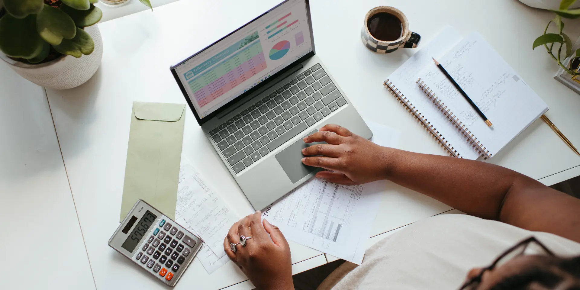 Personne travaillant sur un ordinateur portable avec des documents et une calculatrice