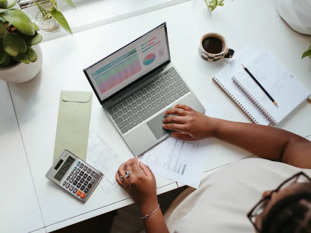 Personne travaillant sur un ordinateur portable avec des documents et une calculatrice