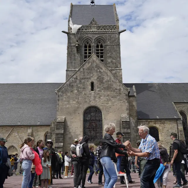 Un couple danse devantl 'église en pierre de Sainte Mere Eglise