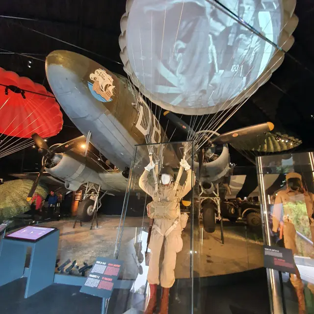 Mannequin en tenue de parachutiste avec parachute ouvert au-dessus d'un avion historique à Airborne Museum de Sainte Mere Eglise