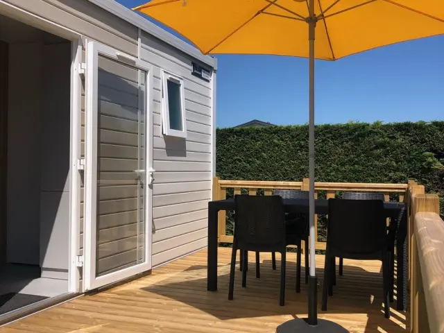 Terrasse en bois avec table, chaises et grand parasol orange