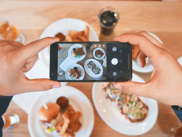 Une personne prend une photo de plusieurs plats avec un smartphone.